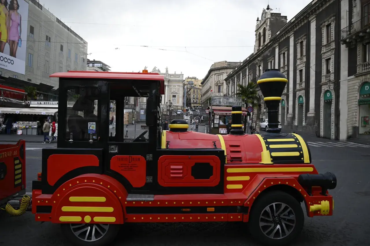 Czerwony pociąg turystyczny "Tourist Dream" na ulicach Katanii, idealny do zwiedzania Syrakuz.