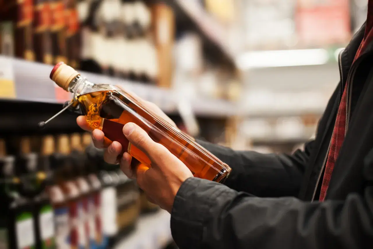 Ręce trzymają butelkę whisky, zastanawiając się, ile alkoholu można przewieźć samolotem z USA do Polski.