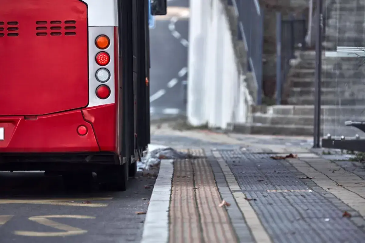 Czerwony autobus 74 stoi na przystanku. Widać jego tylne światła i część karoserii.