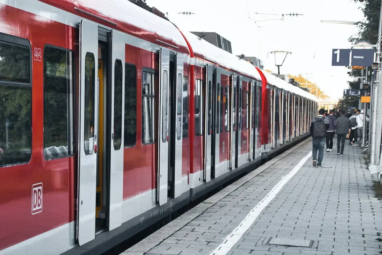 Czerwony pociąg na stacji, ludzie czekają na peronie. Może ktoś właśnie kupił bilet, a teraz zastanawia się nad zwrotem biletu.