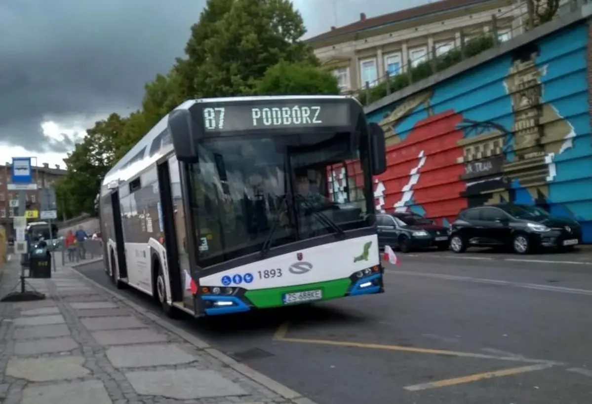 Autobus linii 87 w Szczecinie z napisem "Podwórze" na wyświetlaczu, zbliża się do przystanku.