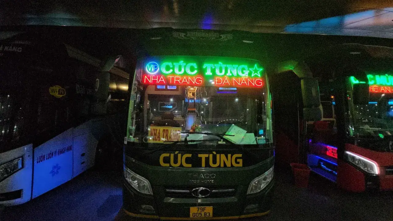 Zielony autobus nocny z neonowym napisem "CÚC TÙNG" i trasą Nha Trang - Da Nang.