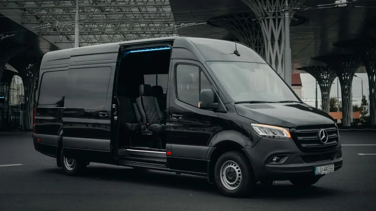 Czarny bus z Niemiec do Polski, z adresu pod adres. Komfortowe fotele i niebieskie oświetlenie wnętrza.