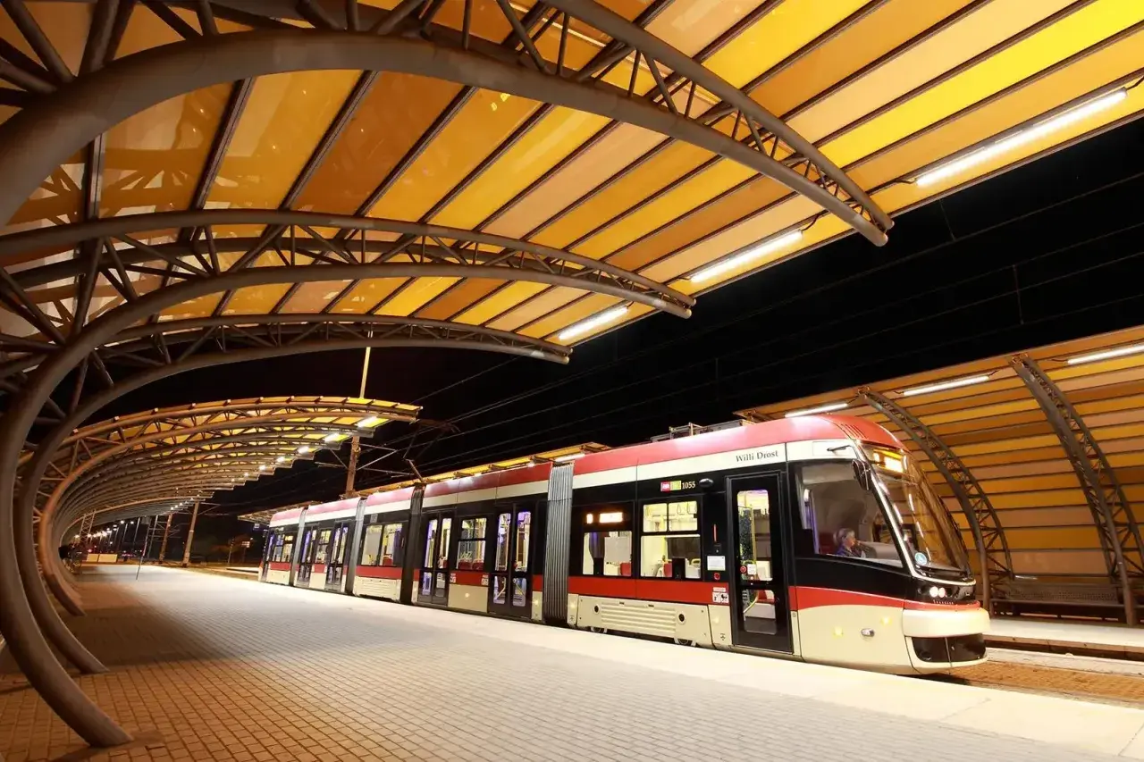 Nowoczesne gdynia tramwaje na peronie pod żółtą, łukowatą wiatą.
