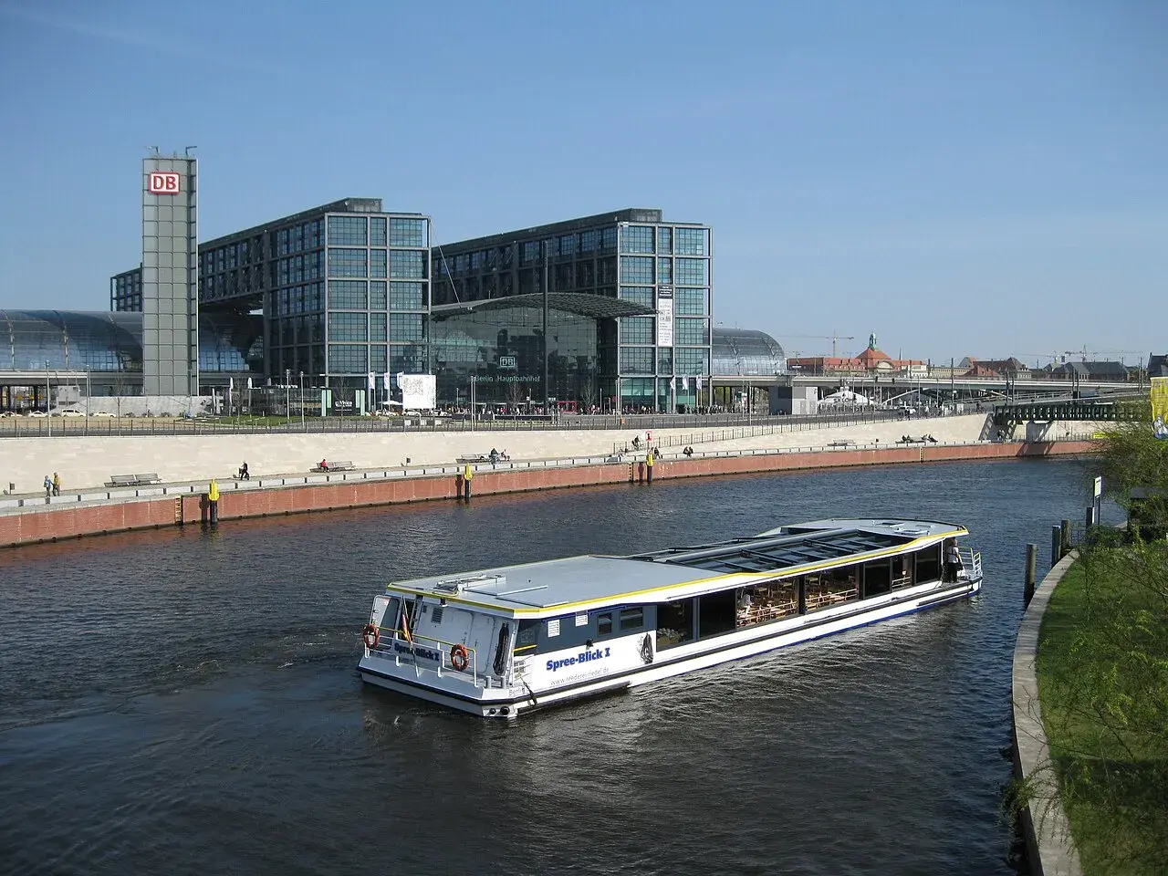Statek wycieczkowy płynie wzdłuż Sprewy obok nowoczesnych budynków Berlin Hauptbahnhof, gdzie znajdują się perony.