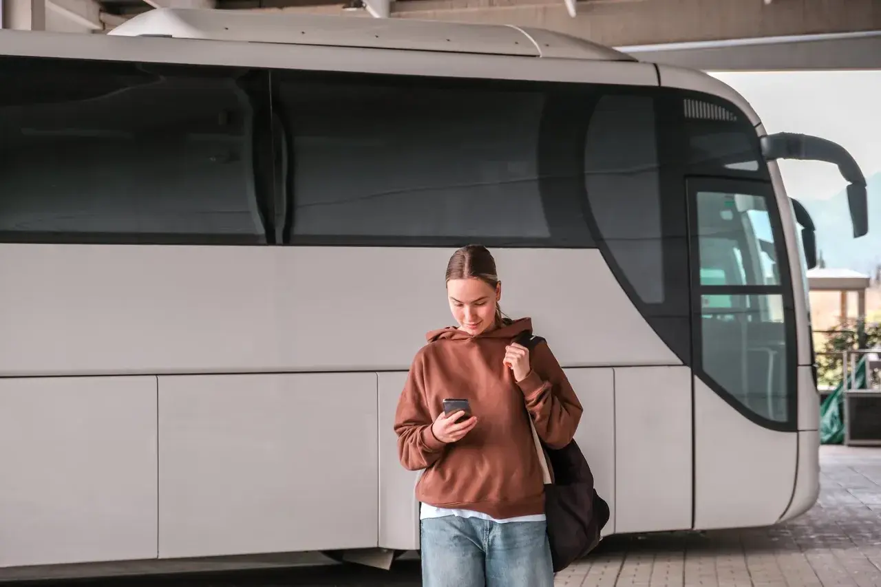 Młoda kobieta z telefonem czeka na autobus, który ma awarię taboru.