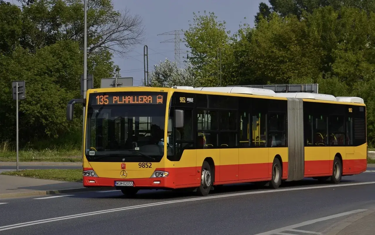 Żółto-czerwony autobus przegubowy linii 135 z napisem "PL.HALLERA" na wyświetlaczu.