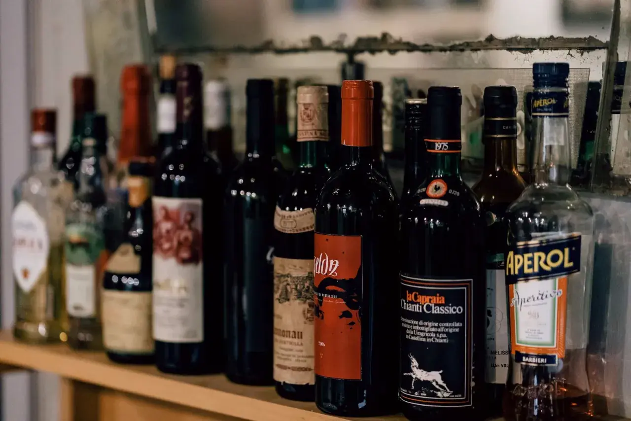 Rząd butelek wina, w tym Chianti Classico, i Aperol. Zastanawiasz się, ile wina można przewieźć z Włoch?