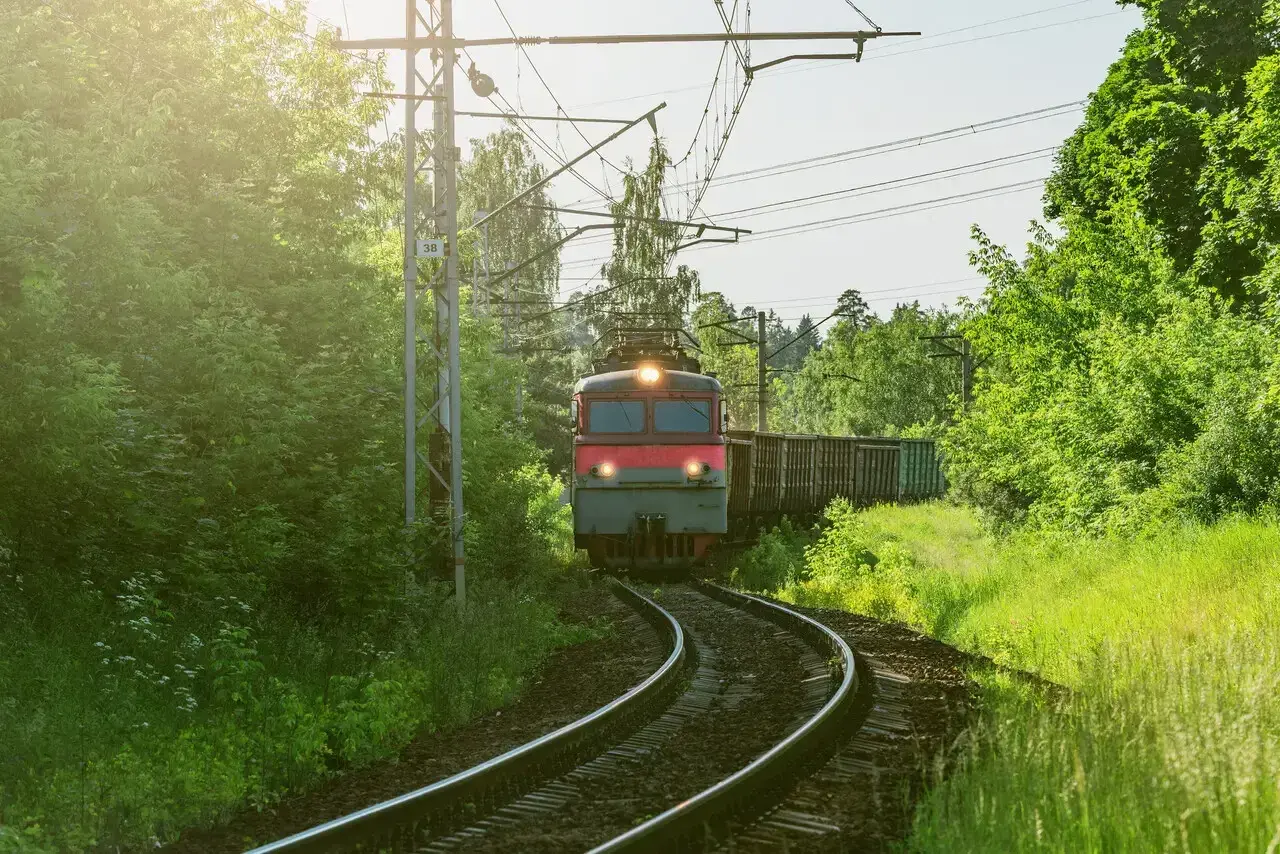 Pociąg towarowy mknie po torach wśród zieleni. Marzysz, jak zostać maszynistą? To podróż pełna odpowiedzialności i pięknych widoków.