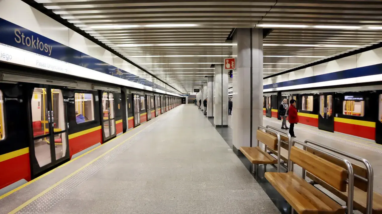 Stacja metra Stokłosy w Warszawie. Pociągi z czerwono-żółtymi pasami czekają na pasażerów.