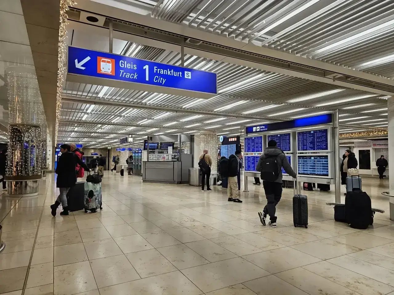 Wnętrze dworca kolejowego na lotnisku Frankfurt nad Odrą. Pasażerowie z bagażami czekają na pociąg do Frankfurtu.
