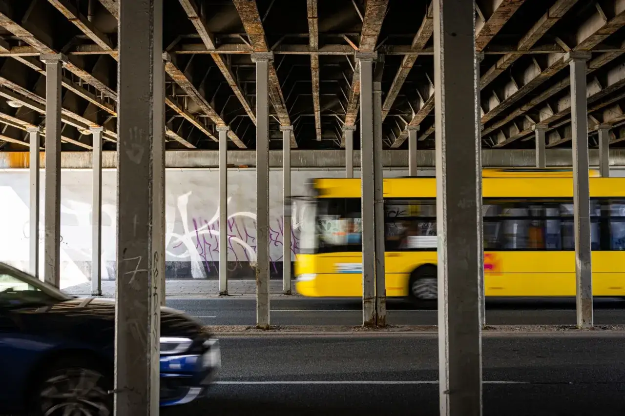 Żółty autobus mija filary pod wiaduktem. Jak dojechać z dworca PKP Katowice na ul. Ceglaną?