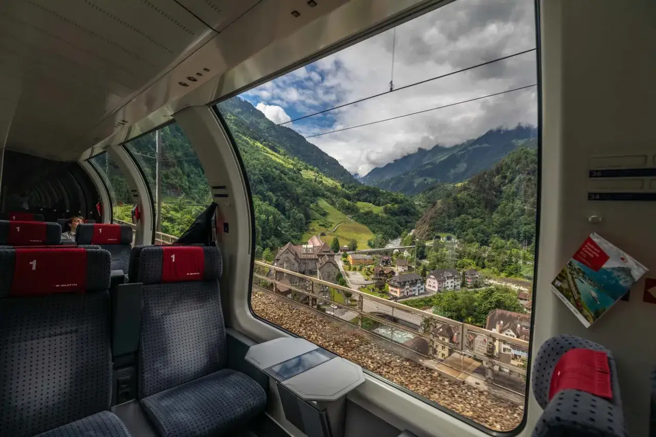 Widok z okna pociągu na alpejską dolinę. Podróż z Swiss Travel Pass to czysta przyjemność.