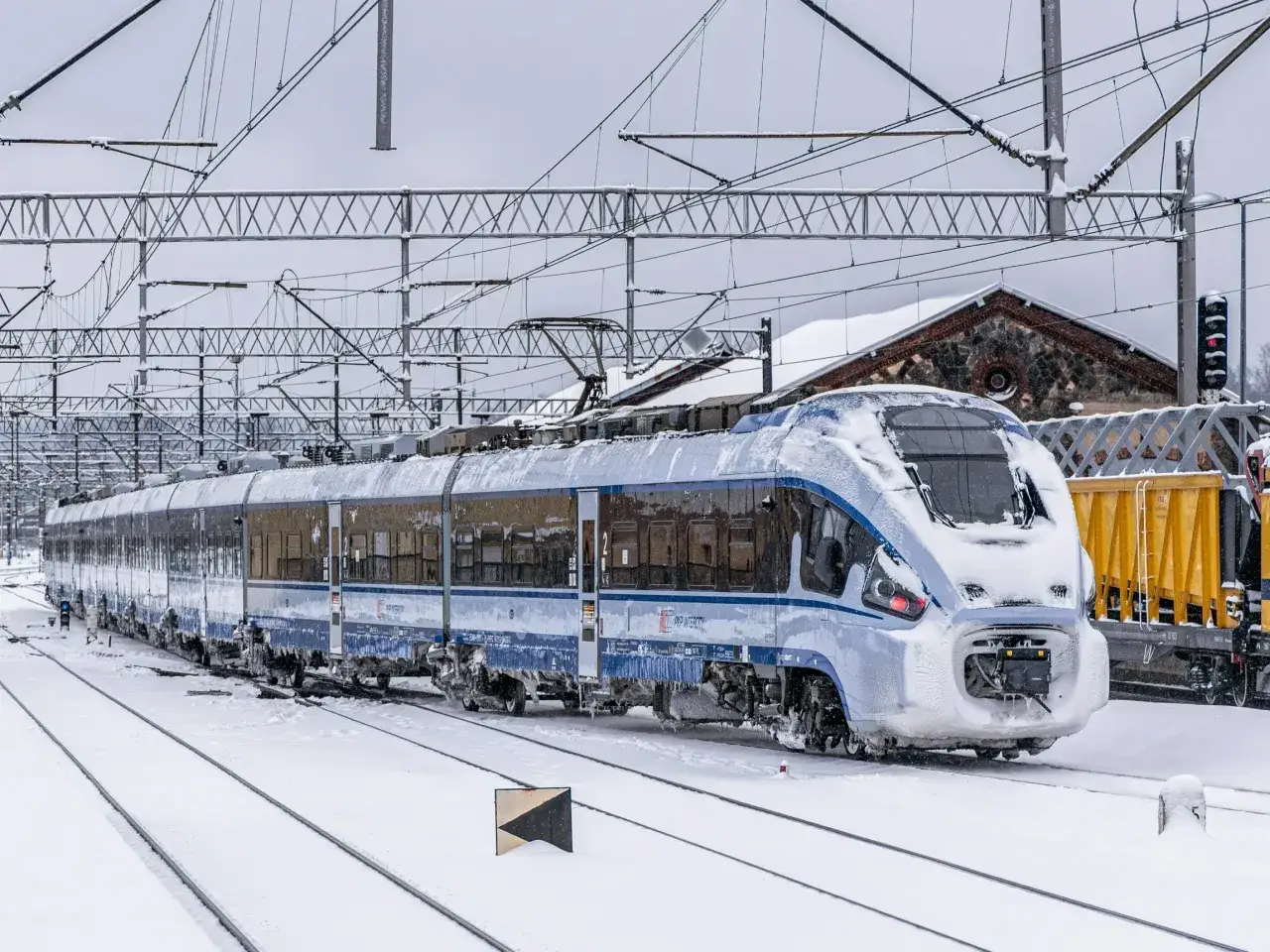 Pociąg PKP Intercity w zimowej scenerii, pokryty śniegiem. Idealny czas na poszukiwanie promocji i podróżowanie.