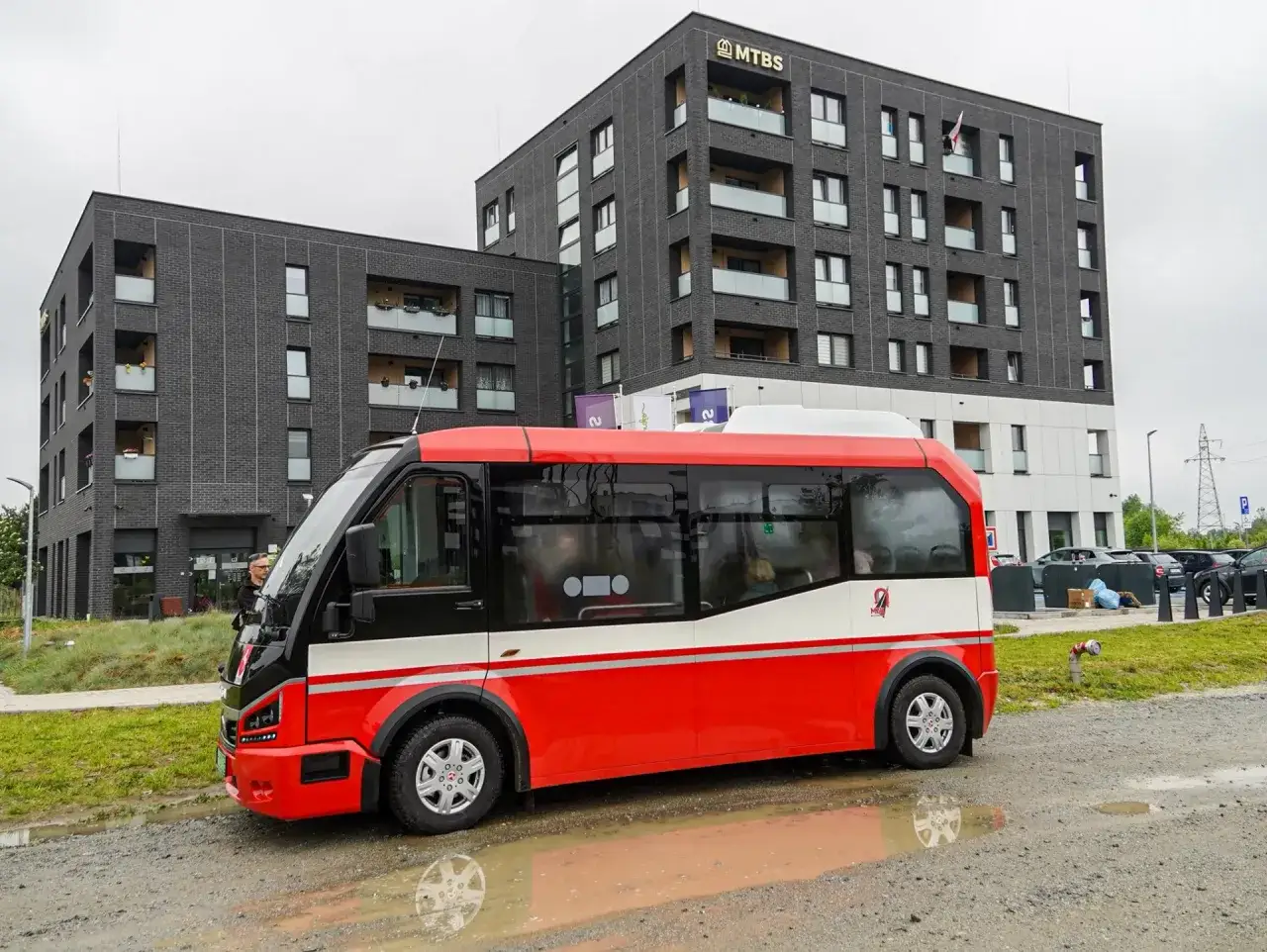 Nowy, czerwono-biały bus czeka na pasażerów. To nowoczesny transport od drzwi do drzwi Polska, zapewniający wygodę i bezpieczeństwo.