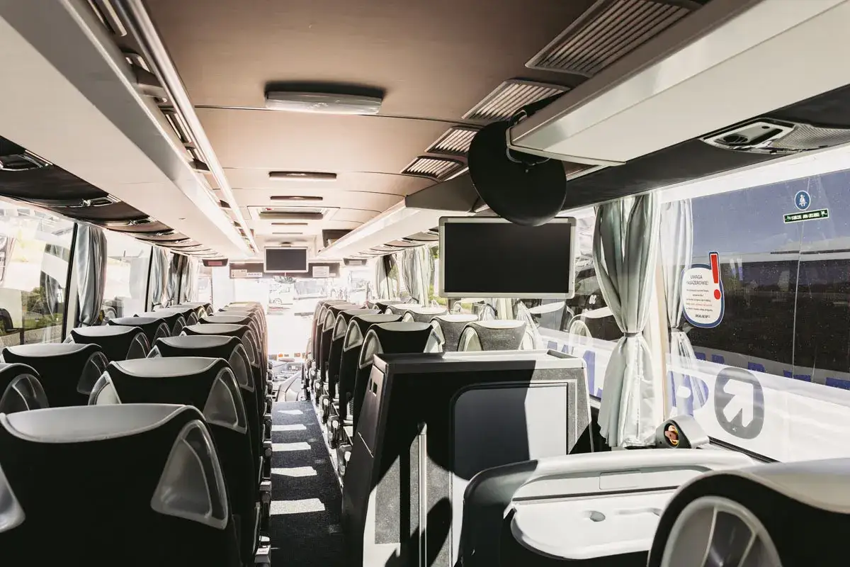 Wnętrze autobusu, rzędy pustych siedzeń, ekrany i okna. Może to być busy Kraków Wiśniowa, gotowy na podróż.