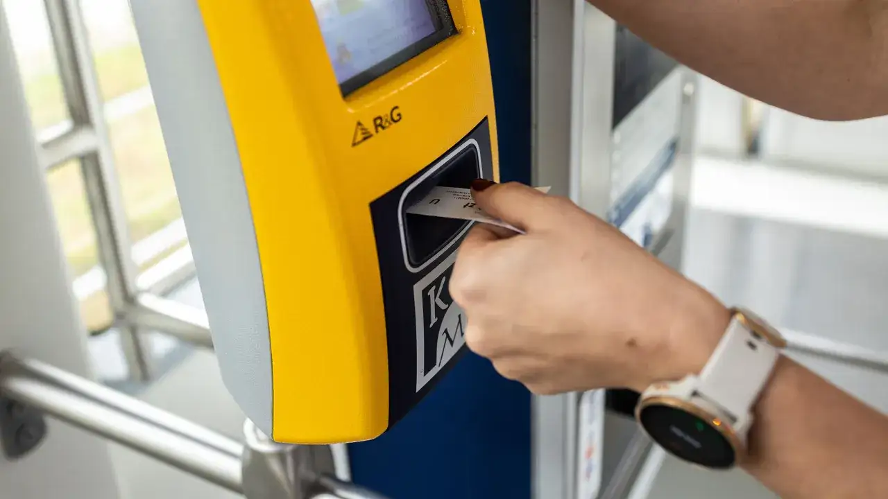 Ręka wkłada bilet dobowy Kraków do żółtego automatu.
