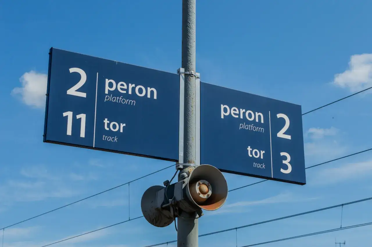 Niebieska tablica informacyjna na słupie pokazuje, jak sprawdzić który peron: peron 2, tor 11 oraz peron 2, tor 3.