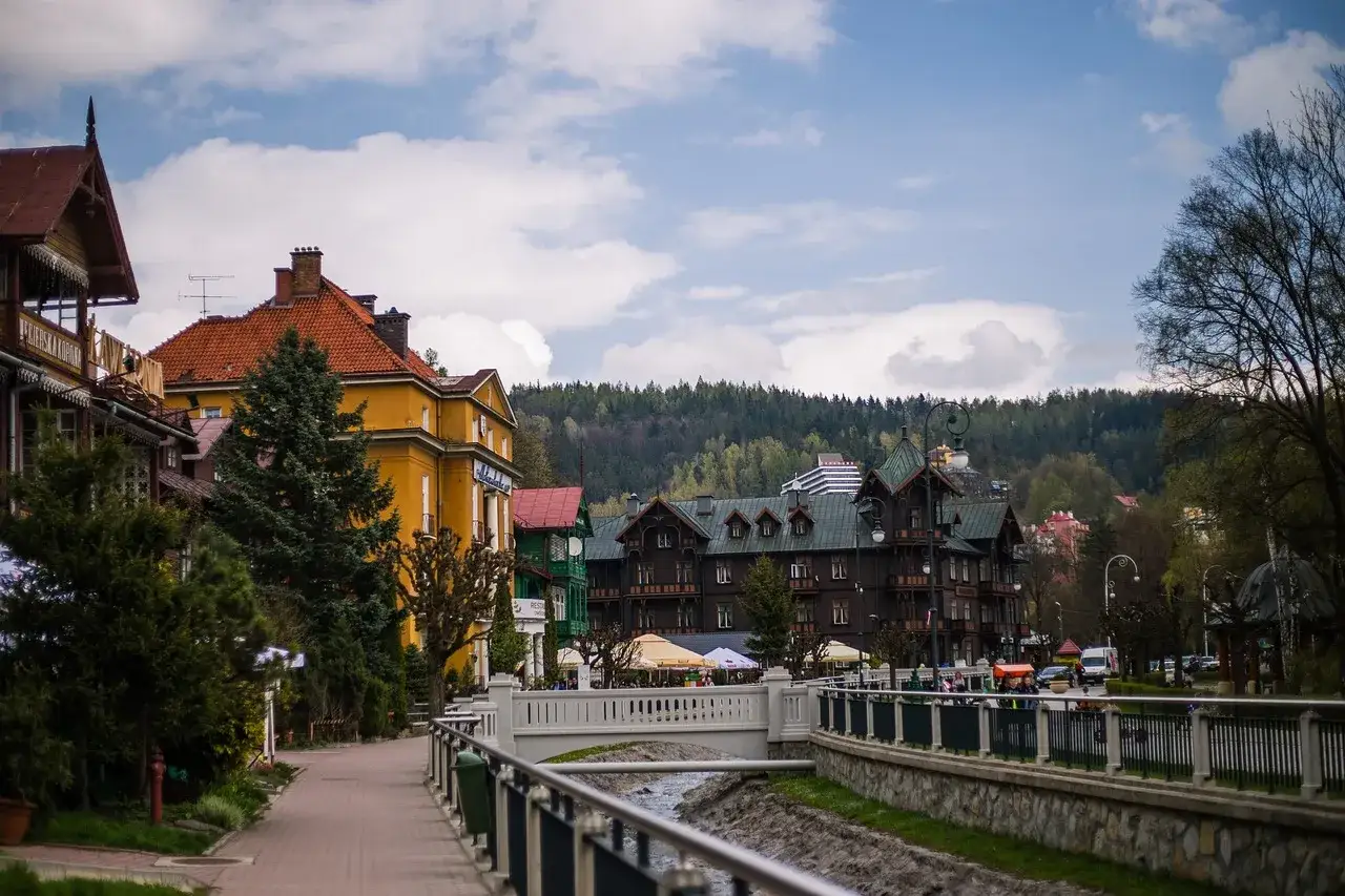 Urokliwa promenada w Krynicy-Zdroju, z widokiem na zabytkowe pensjonaty i wzgórza. Jakby podróż z Warszawy Zachodniej do tego uzdrowiska, gdzie Polonus wita gości.
