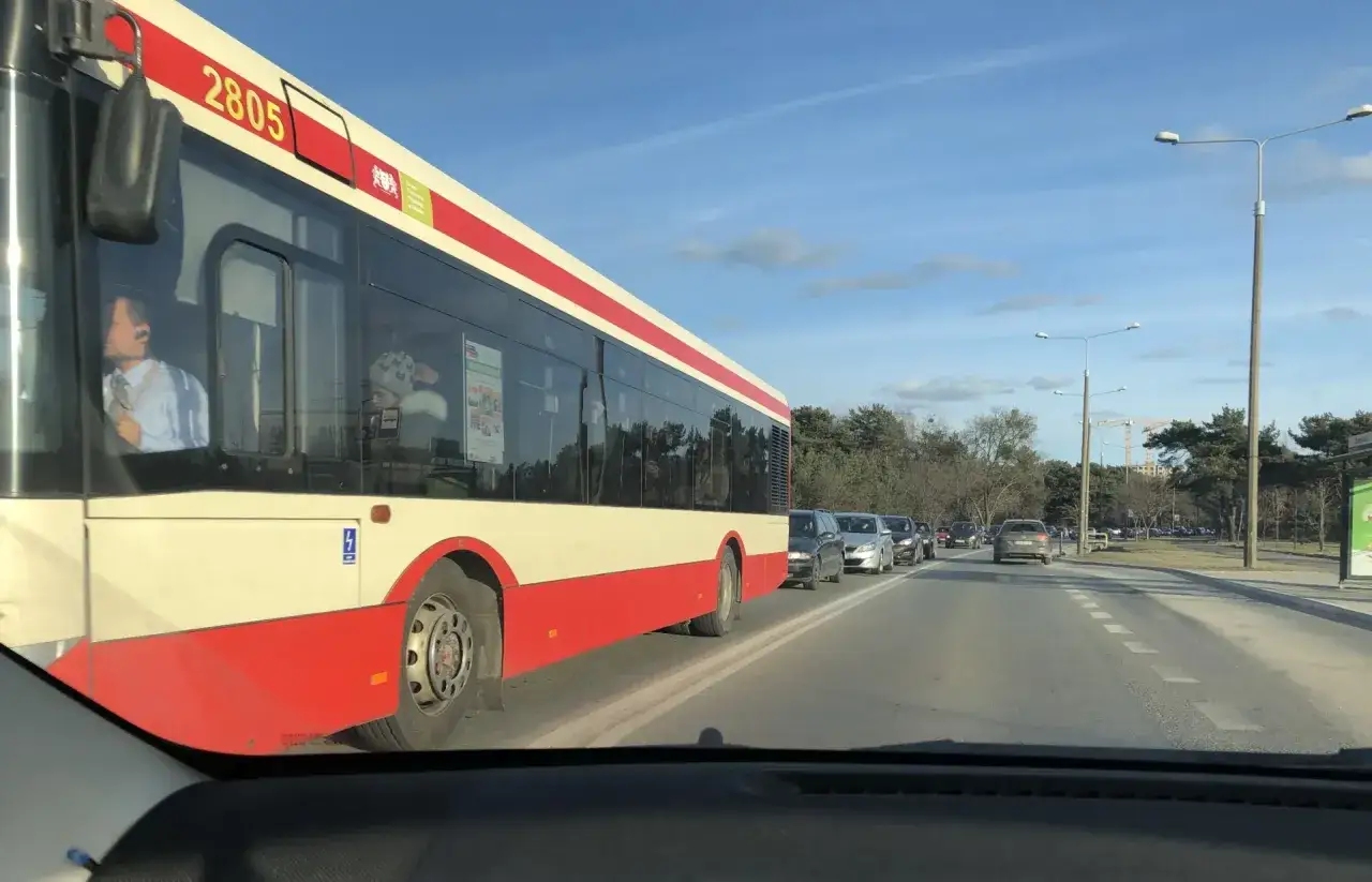 Autobus linii 148 Gdańsk stoi w korku. Widać pasażerów w środku.