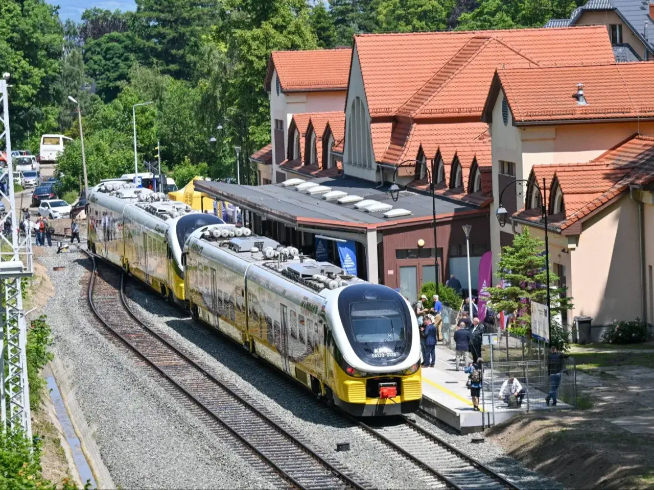 Nowoczesny pociąg PKP SKROT stoi na peronie przy urokliwym dworcu.