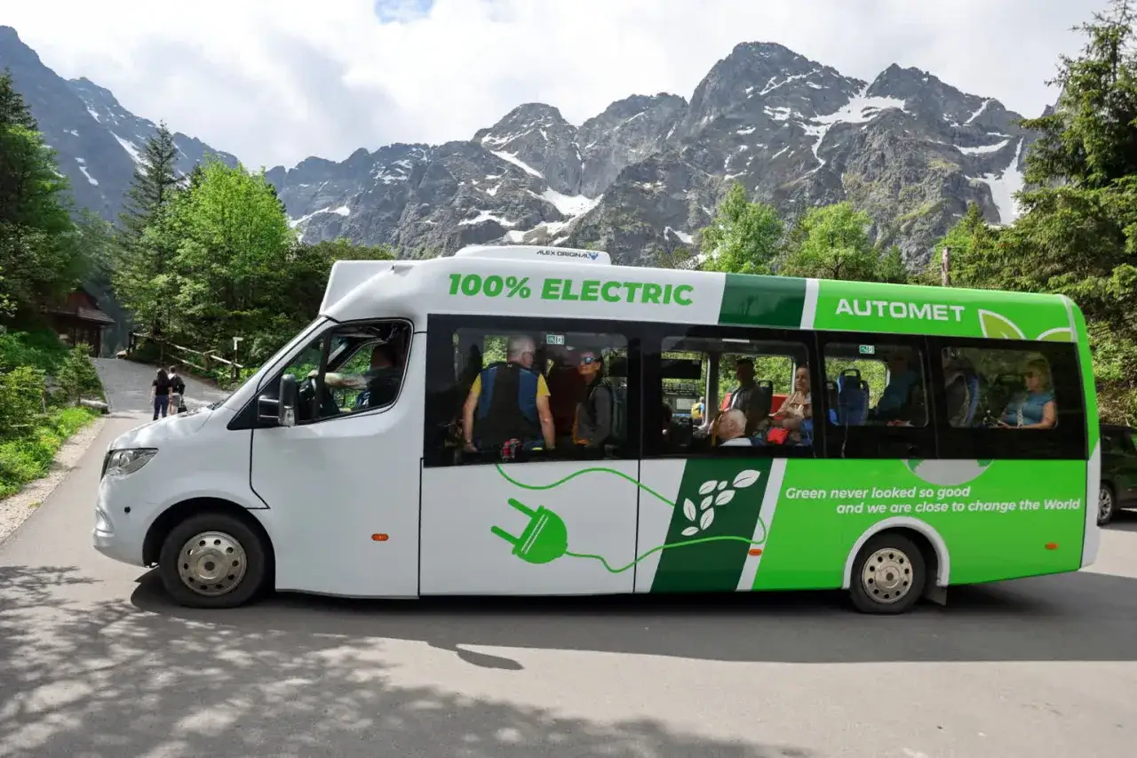 Elektryczny bus Automt na Morskie Oko, z pasażerami w środku, na tle gór.