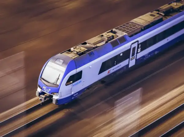 Niebiesko-biały pociąg PKP Stadler mknie po torach. Zastanawiasz się, ile kosztuje bilet ulgowy PKP?